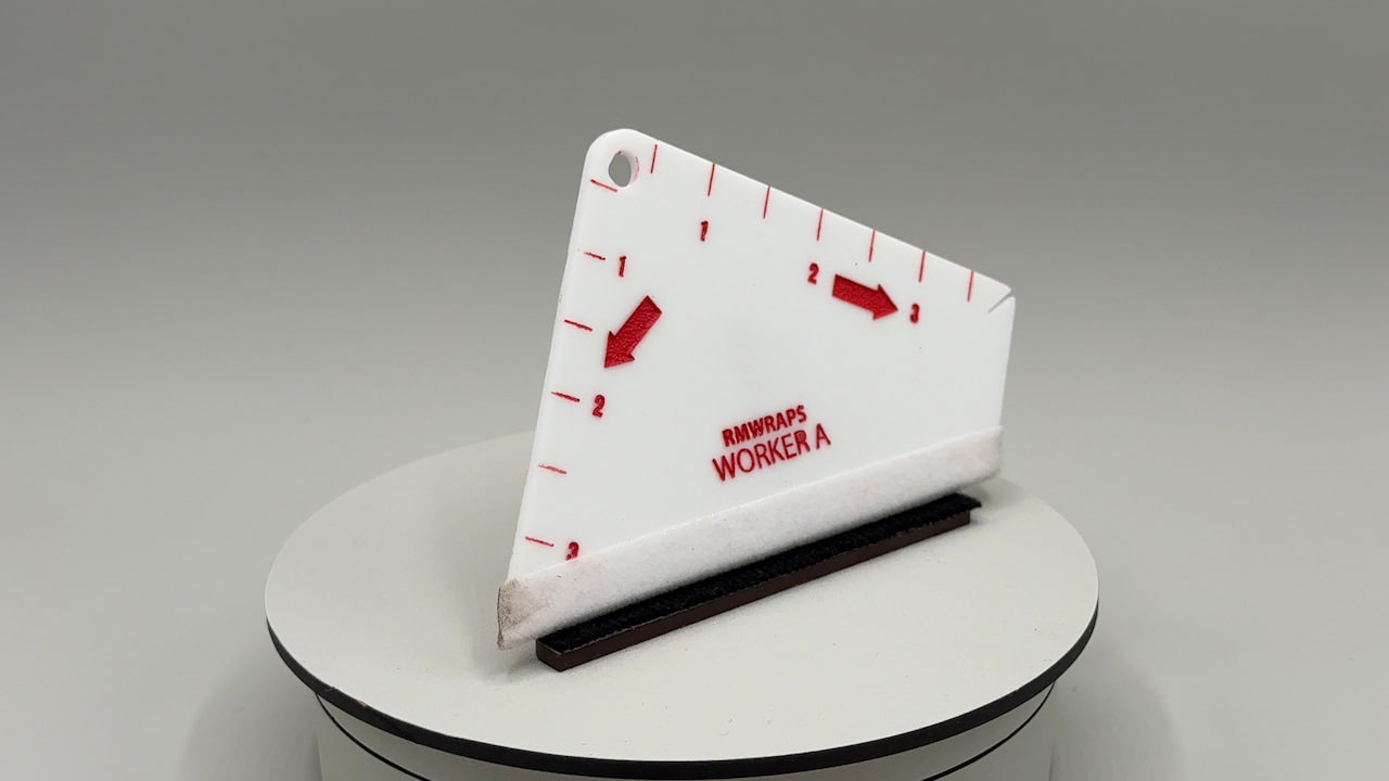 White triangular ruler with red markings and text on a gray background