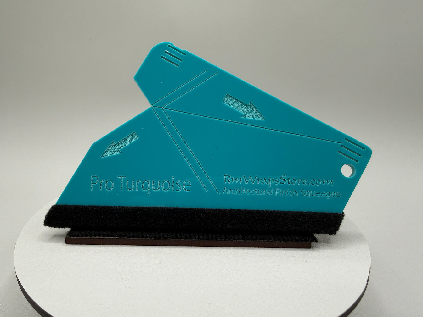 Turquoise paint scraper on a white platform with a gray background