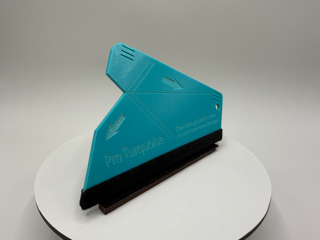 Teal squeegee on a white stand with a gray background