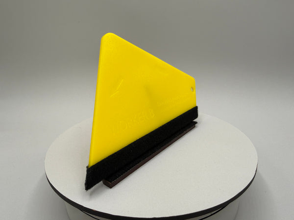 Yellow triangular squeegee on a white platform with a gray background