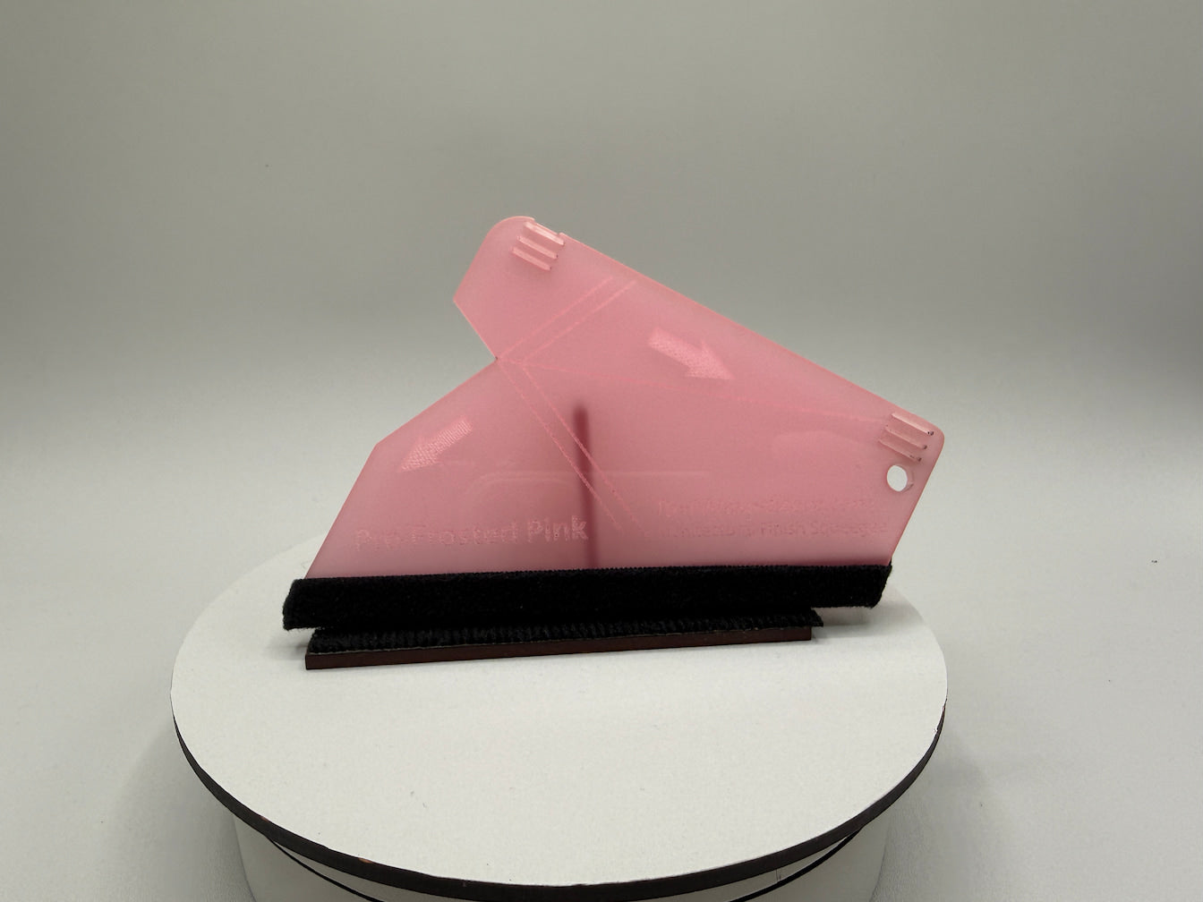 Pink squeegee on a white surface with a gray background