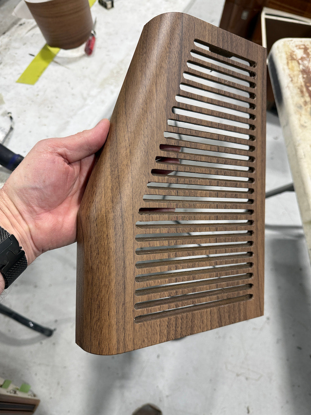 Hand holding a wooden air vent cover on a blurred background